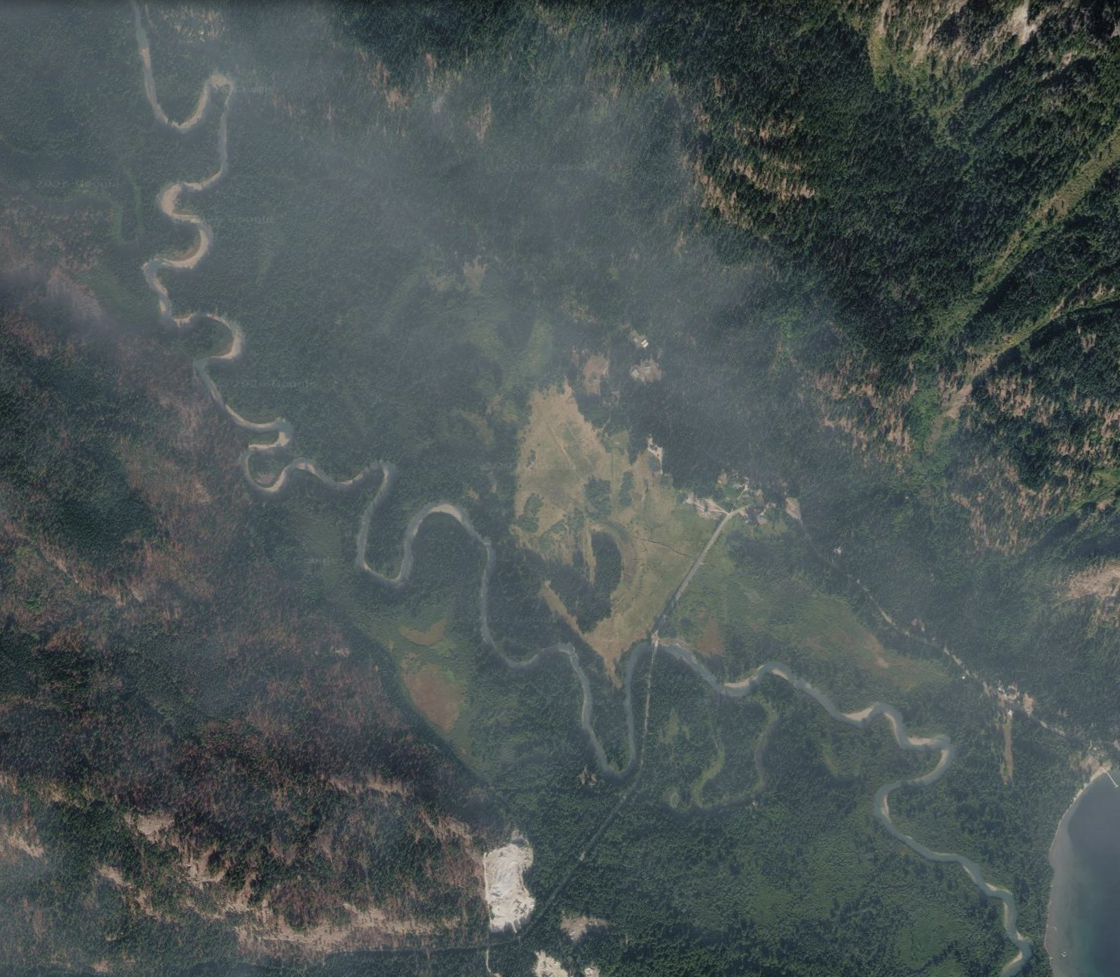 Satellite imagery of a subalpine river winding through a lush green landscape.